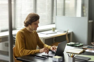 Profesional de RRHH trabajando en un portátil calculando el índice de absentismo laboral y los costes ocultos de las bajas en una empresa de transporte
